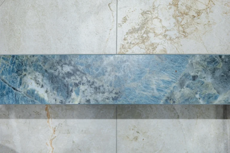 Cream stone-effect wall tiles with a band of blue marble-effect tile running across them