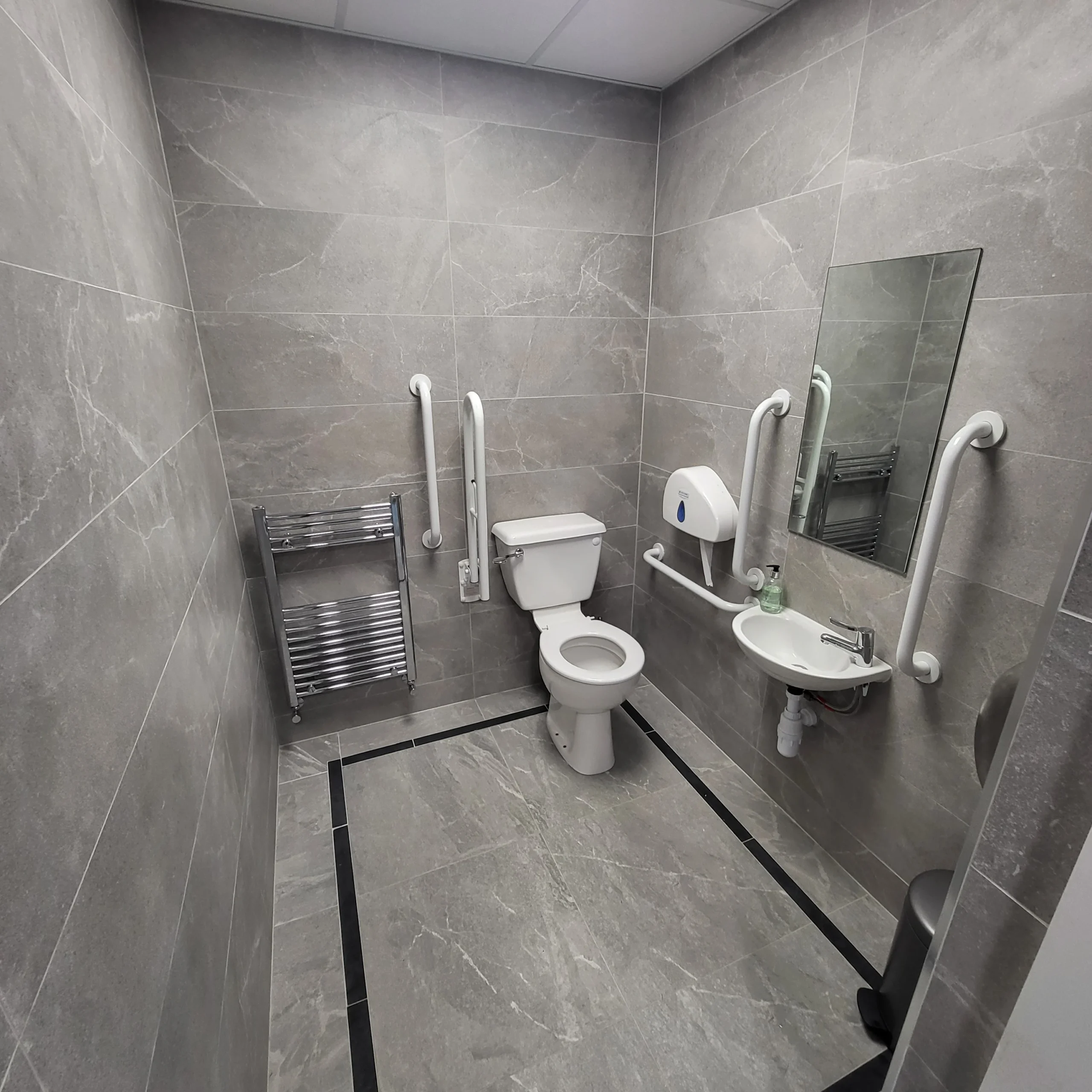 Accessible bathroom renovation with grey marble effect tiles and practical sanitaryware