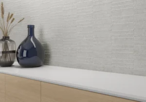 Pearl grey linear décor wall tiles behind a worktop with blue ceramic vases