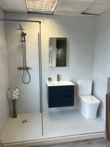 Showroom bathroom with white textured wall tiles, walk-in shower and navy vanity unit