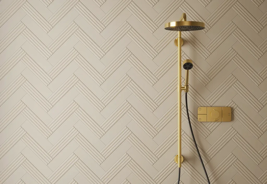 Cream ridged wall tiles in herringbone layout alongside a brushed gold shower system