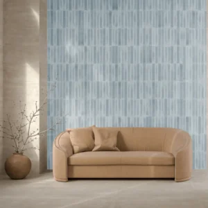 Pale blue ribbed wall tiles behind a curved camel sofa in a styled living room