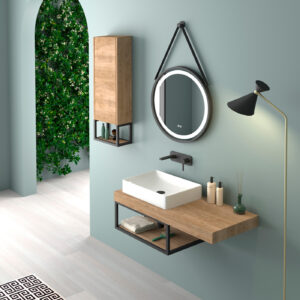 Rectangular white countertop basin on oak open shelf unit with round strap mirror on sage green wall