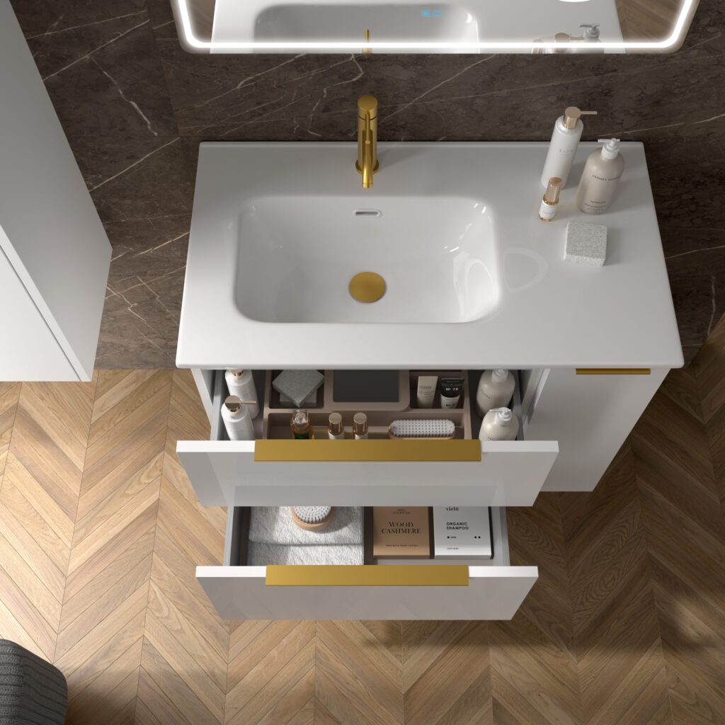 Overhead view of open white vanity drawers with gold handles revealing neatly organised bathroom essentials