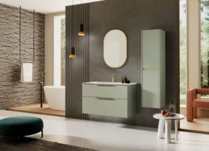 Matte leaf green wall hung vanity with gold oval mirror and matching tall cabinet against a dark fluted wall