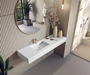 White wall-mounted washbasin with gold tap styled in a neutral bathroom with round mirror