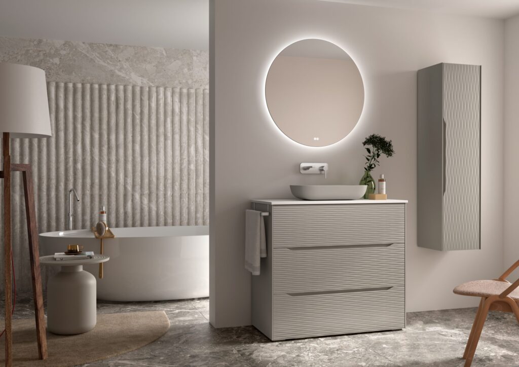 Greige ribbed 1000mm vanity unit with round backlit mirror and tall wall cabinet beside a freestanding bath
