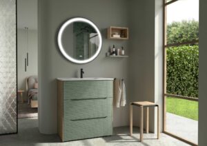 Sage green ribbed vanity unit with round LED mirror beside a large window overlooking a garden