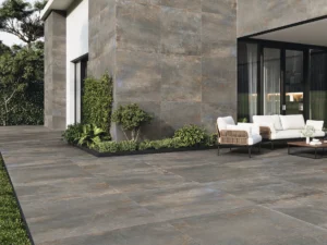 Dark metal-effect porcelain tiles on an outdoor terrace and feature wall with garden seating