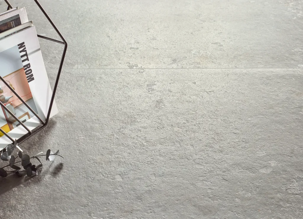 Textured light grey stone-effect floor tiles styled with a geometric magazine holder