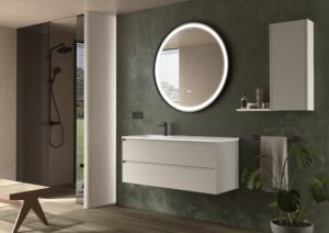 White wall hung vanity unit with round illuminated mirror against a deep green textured wall