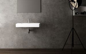 White wall-hung washbasin with chrome tap against a concrete-effect grey wall