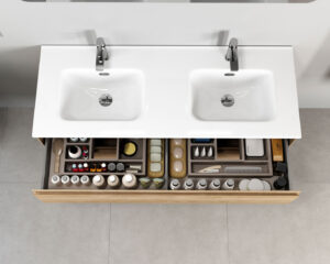Overhead view of double basin vanity with two open drawers filled with organised toiletries