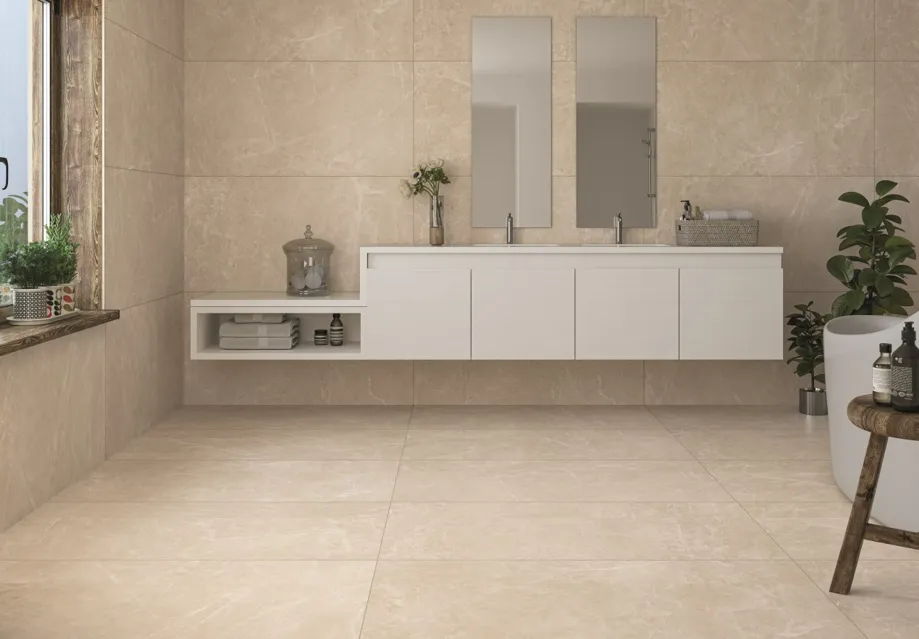 Spacious bathroom clad floor to ceiling in cream satin marble-effect tiles with white vanity unit
